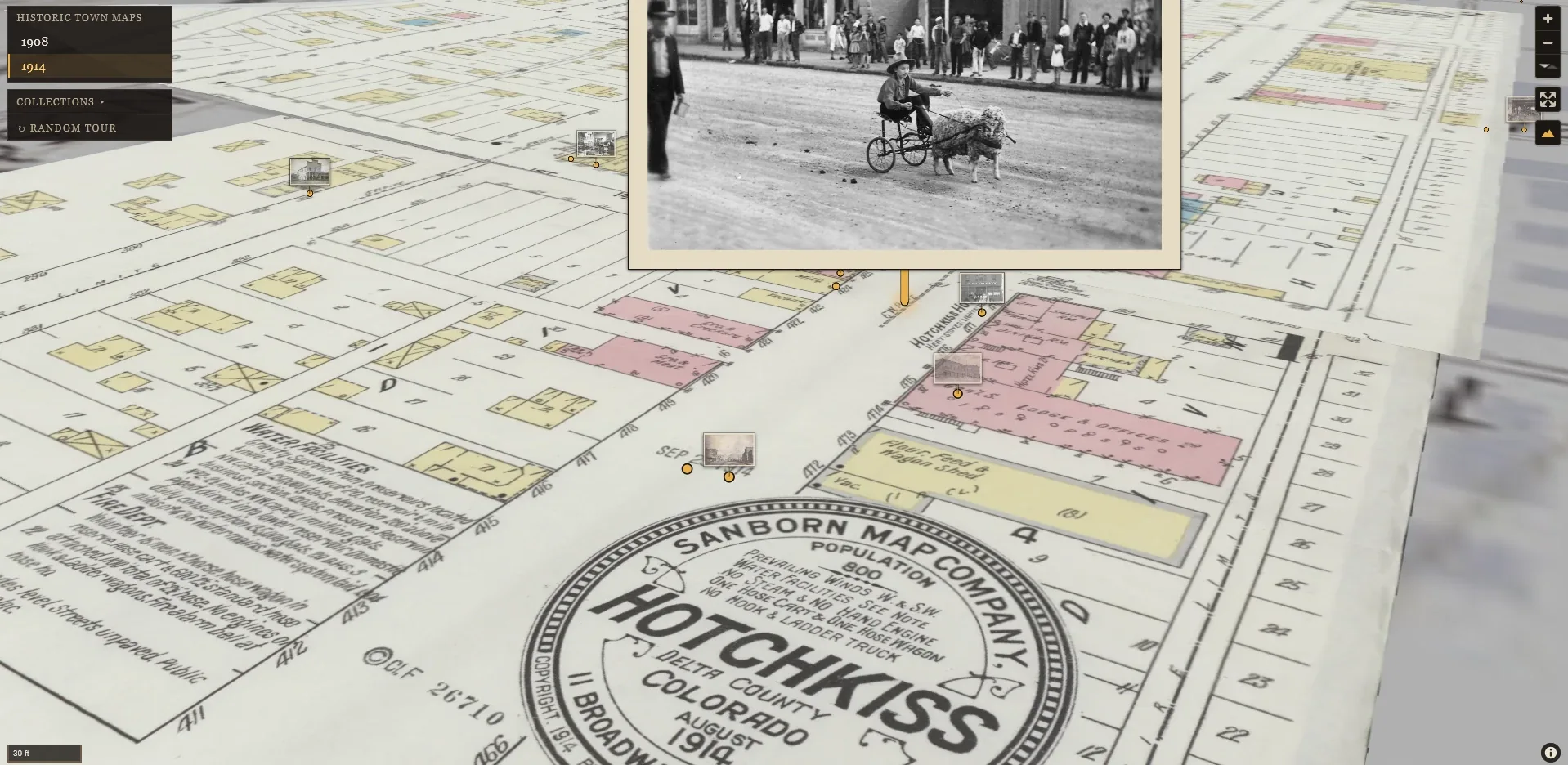 map.hchsmuseum.org: the 1914 Sanborn fire-insurance map of Hotchkiss, historic photographs pinned where they were taken; one stands open over Main Street, a boy driving a cart drawn by a sheep.